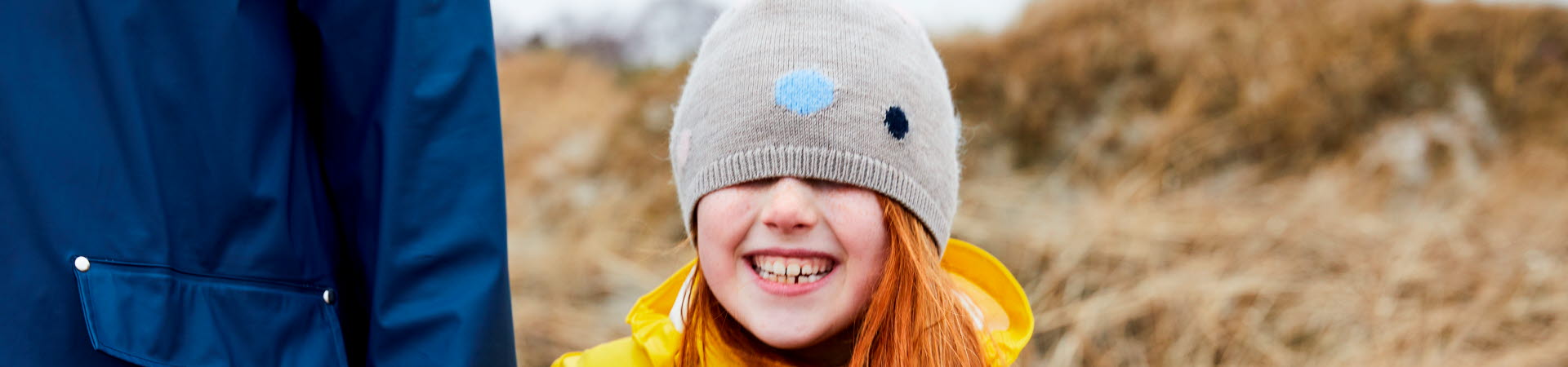 Flicka med gul regnkappa på en strand