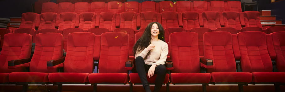 Ungdom sitter på en röd biografstol i kulturbiografen