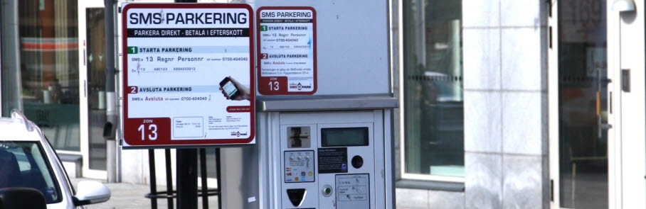 En parkeringsautomat med en skylt som instruerar hur man sms-parkerar.