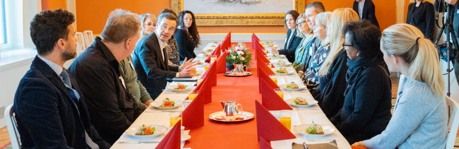 Frukostmöte med statsministern 28 november. Statsministern och flera familjehem sitter runt ett bord.