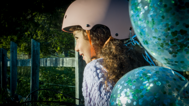 Profilbild bild på cyklande flickas ansikte med ballonger fladdrande bakom.